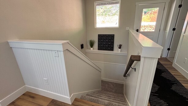 Un escalier avec une rampe blanche, une petite plante en pot et un cadre photo accroché au mur.