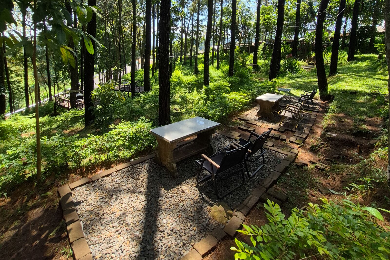 An outdoor seating area with a table and chairs, surrounded by a forested environment.
