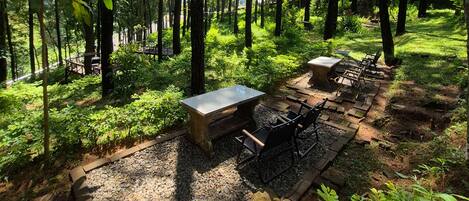 An outdoor seating area with a table and chairs, surrounded by a forested environment.