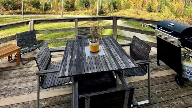 A wooden deck with a table and chairs, a grill, and a view of a natural landscape with trees and hills. - Three Peaks Hideaway, a Tranquil 4-bedroom house with Mountain Views in Peru (Peru)