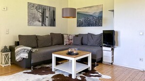 Ein Wohnzimmer mit einer Couch, einem Couchtisch, einem Fernseher und Kunstwerken an den Wänden.