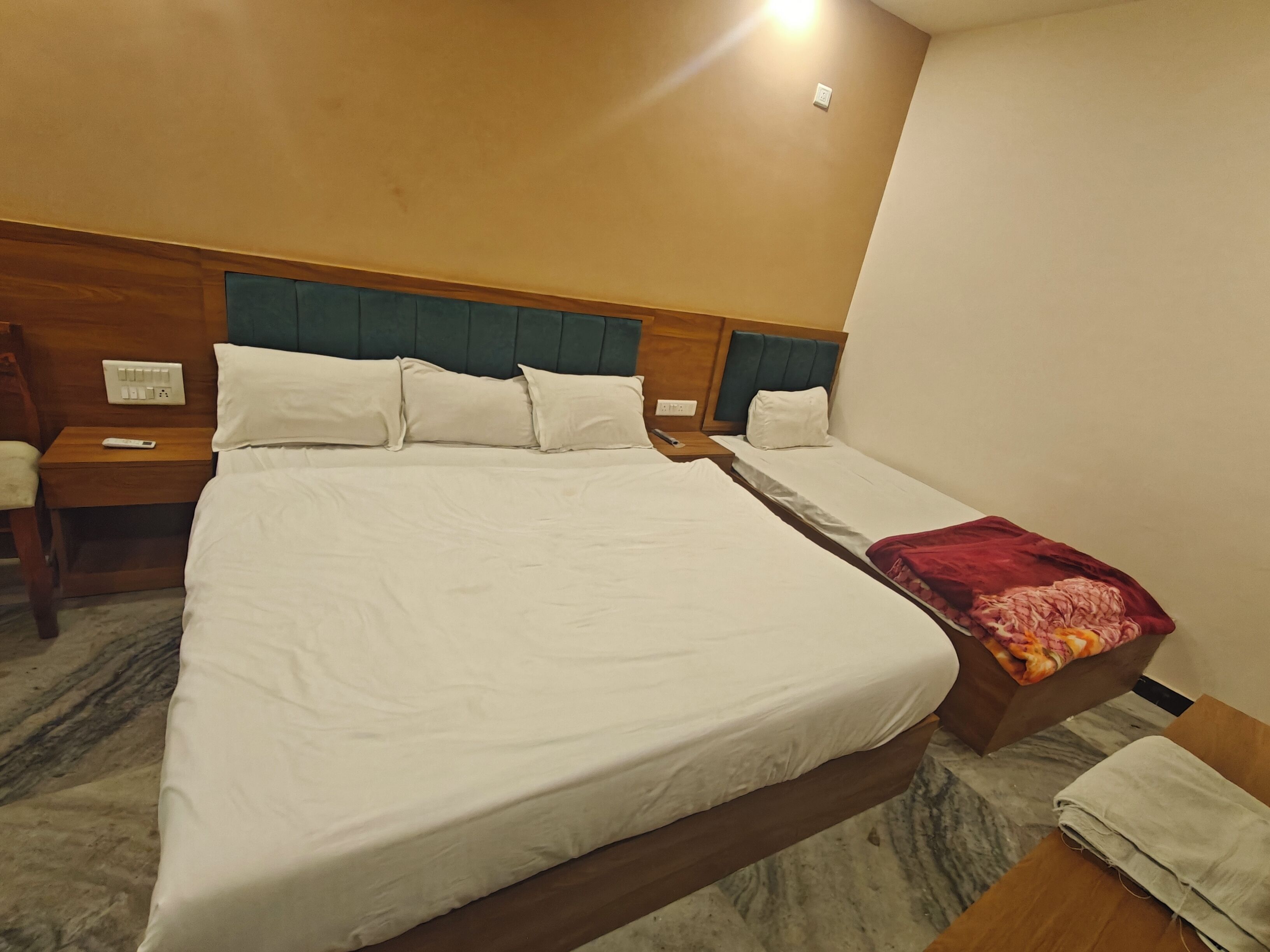 A hotel room with a large bed, two bedside tables, a nightstand, and a wooden headboard.