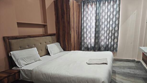 A neatly made bed with a wooden headboard and a marble-patterned floor. - The haveli lounge and restaurant (Udaipur)