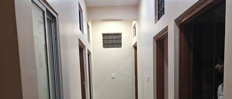 A hallway with a marble floor, wooden doors, and a ceiling with recessed lighting.