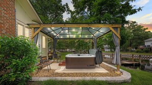 Ein Whirlpool unter einem gläsernen Pavillon mit Liegestuhl und Sonnenschirm.