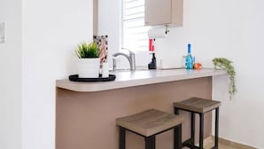Una cocina moderna con encimera blanca, un lavabo y dos taburetes.