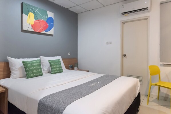 Una habitación de hotel con una cama, una mesita de noche, una silla y un aire acondicionado de pared.