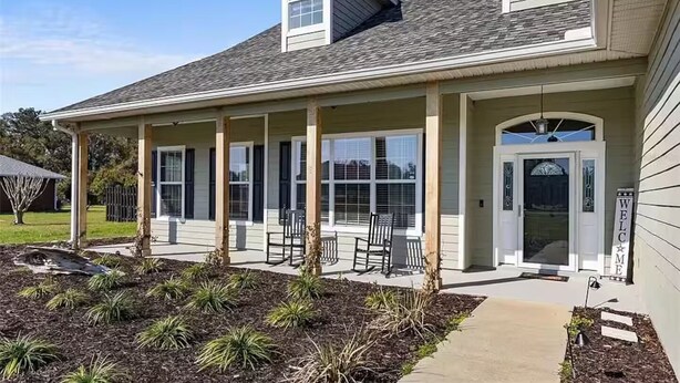 A two-story house with a covered porch, a front door with a 'WELCOME' sign, and a small garden area with plants. - Ranch House w/ Pools, Pickleball, Sand Volleyball 10 mins to Springs (High Springs)