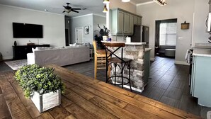 A modern kitchen with a central island, wooden flooring, and pendant lighting. - Ranch House w/ Pools, Pickleball, Sand Volleyball 10 mins to Springs (High Springs)
