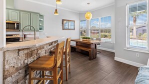 A modern kitchen with a stone island, wooden chairs, and pendant lighting. - Ranch House w/ Pools, Pickleball, Sand Volleyball 10 mins to Springs (High Springs)