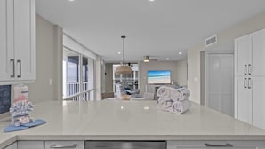 Una cocina moderna con armarios blancos, un lavavajillas de acero inoxidable y una isla grande con toallas.
