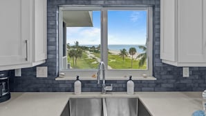 Una cocina con un amplio ventanal con vistas a un campo de golf y una playa.