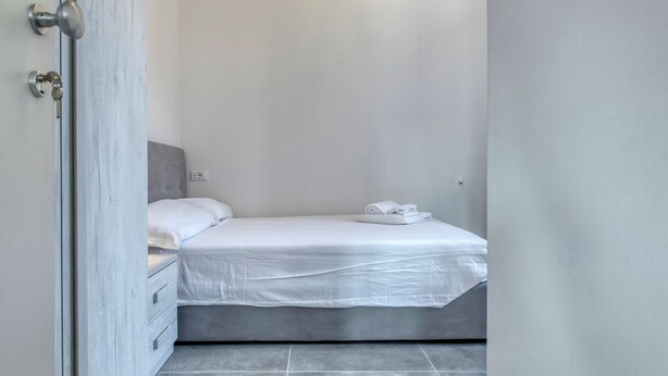 A bedroom with a bed, a nightstand, and a door. - Suite Clapton | BluesHouse Carracci Suites (Bologna)