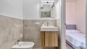 A modern bathroom with a sink, mirror, and shower. - Suite Clapton | BluesHouse Carracci Suites (Bologna)
