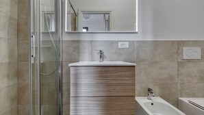 A modern bathroom with a glass shower enclosure, a wooden vanity with a sink, and a bidet. - Suite Hendrix | BluesHouse Carracci (Bologna)