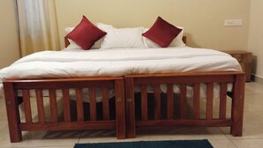 Una cama doble con dos cabeceros de madera, ropa de cama blanca y dos almohadas rojas.