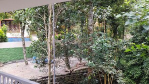 Un balcón con vistas a un jardín, un muro de piedra y un edificio de fachada azul y blanca.