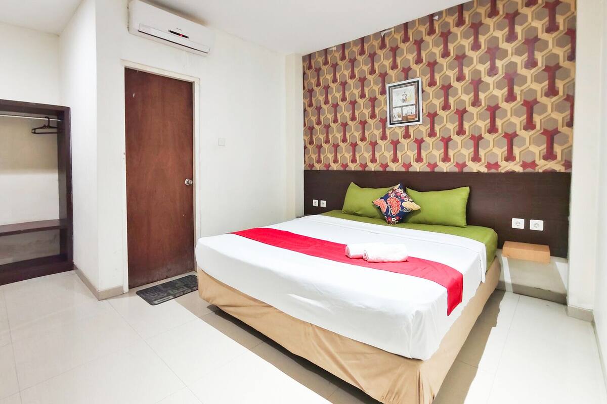 Quarto de hotel com cama, guarda-roupa, porta e parede estampada.