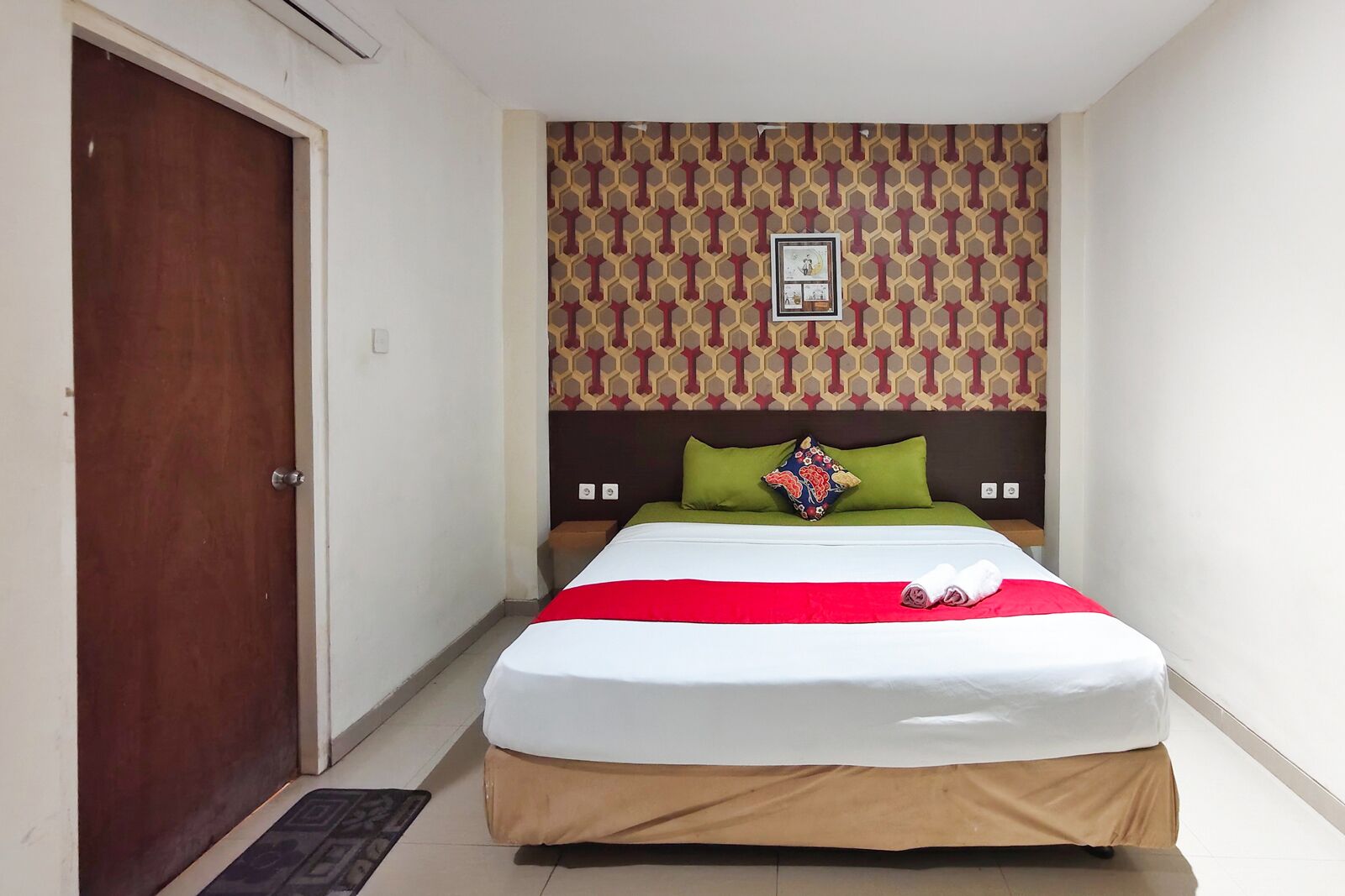 Une chambre d’hôtel avec un lit, une porte et un mur décoré de motifs.
