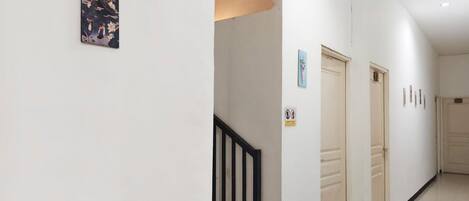 A hallway with white walls, a black railing, and doors with a 'No Entry' sign.