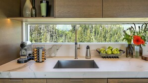 A modern kitchen with a large window, a built-in espresso machine, a fruit bowl, and a vase with flowers. - Healdsburg Modern Retreat - Pool, Views & Design (Healdsburg)