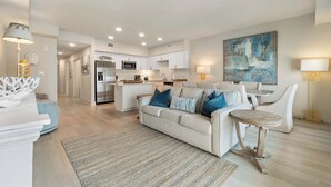 A modern living room with a sofa, a coffee table, and a kitchen in the background.