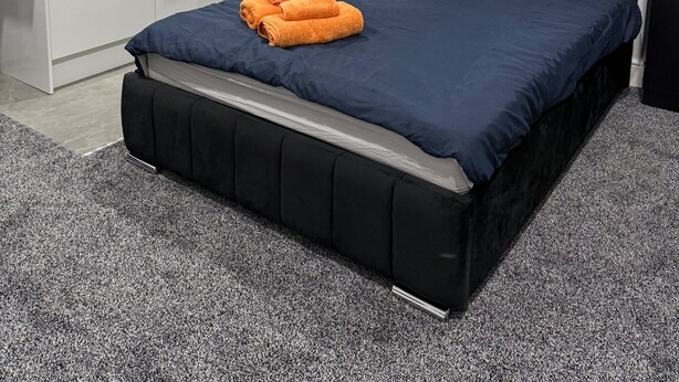 A modern bedroom with a black bed, a blue mattress, and an orange towel. - Studio - Sleeps 2 - Parking - Wifi (Luton)