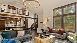 Uma sala de estar espaçosa com uma janela grande, uma escada que leva a um andar superior e uma cozinha com eletrodomésticos modernos.