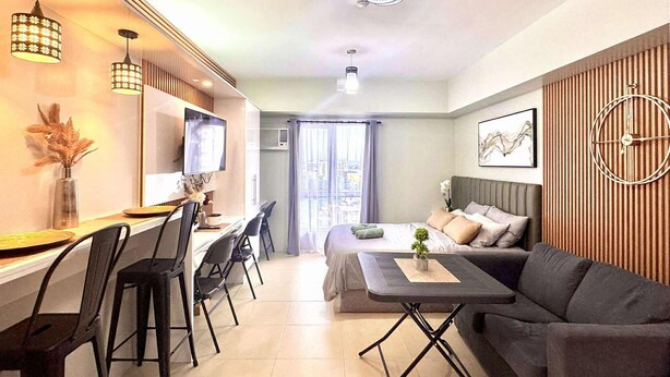 Ein modernes Hotelzimmer mit einem Bett, einer Couch, einem Schreibtisch mit Stühlen und einem Fernseher.