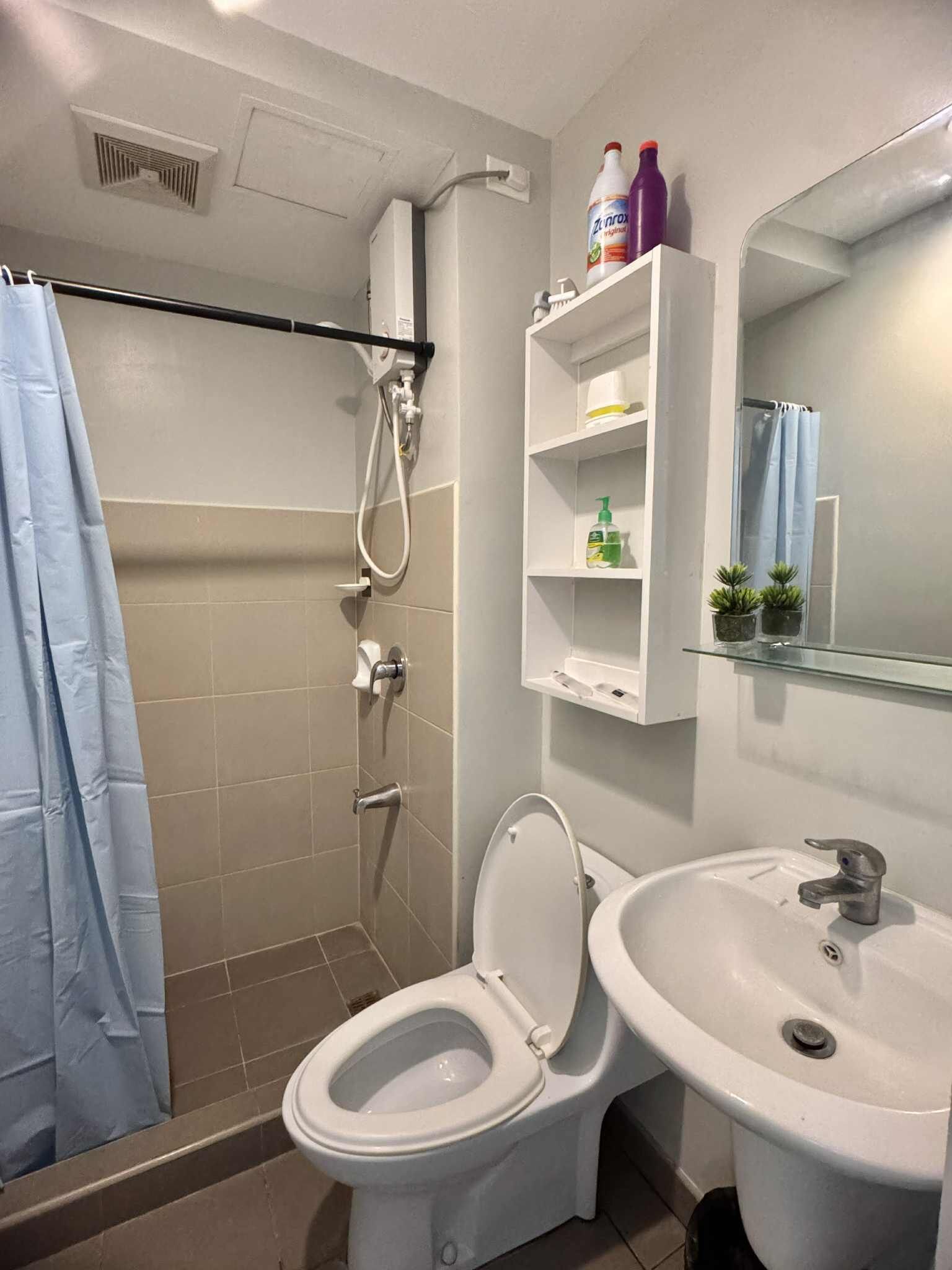 Ein Badezimmer mit Toilette, Waschbecken, Dusche und einem Ablagefach für Toilettenartikel.