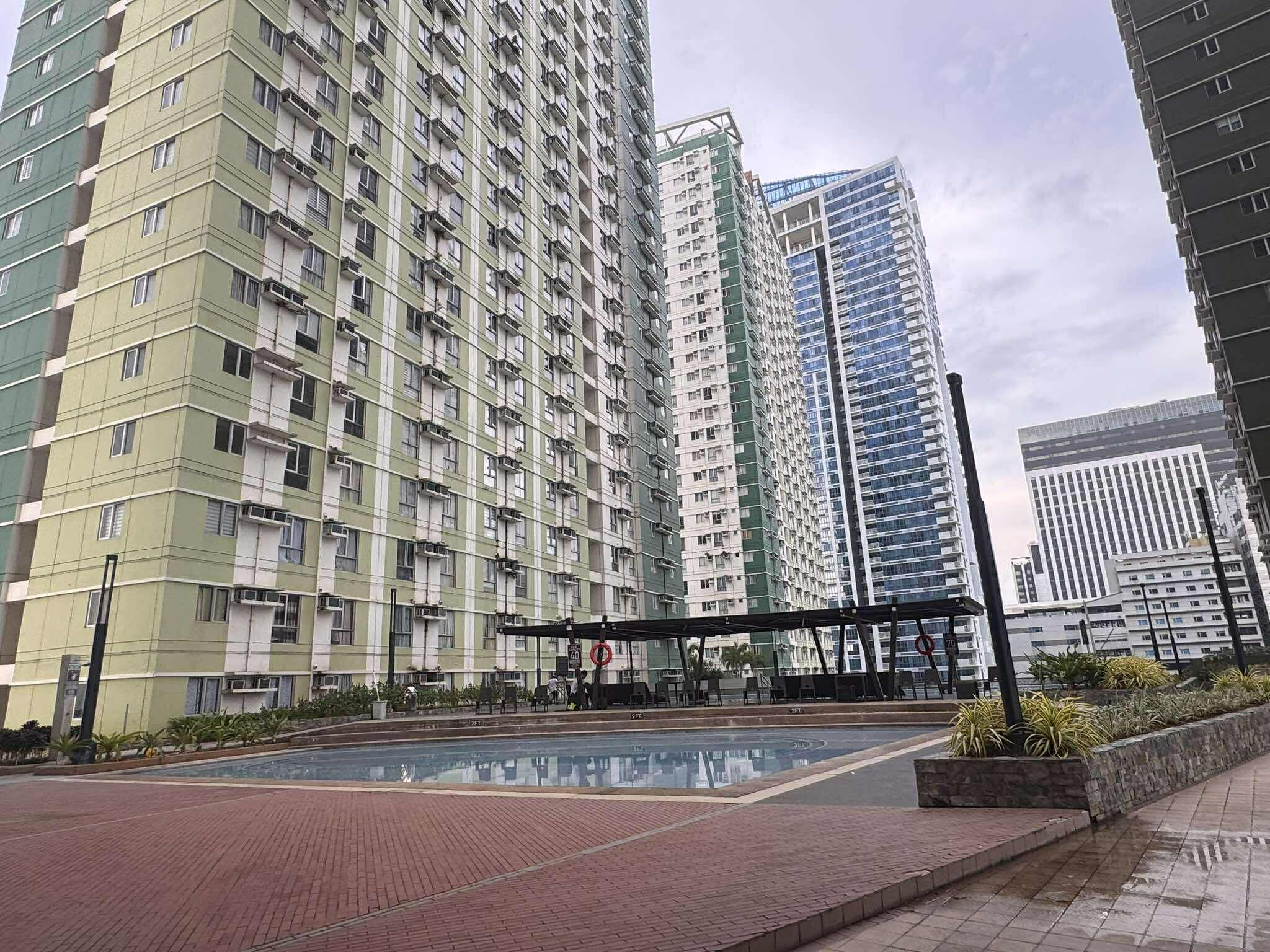 Un edificio residencial alto con múltiples balcones y una piscina reflectante al frente.