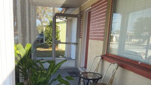 A covered outdoor area with a potted plant, a table, and two chairs. - beaches house near by beach (Holiday)