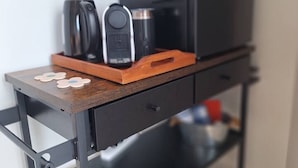 Angolo cottura con macchina del caffè, bollitore e forno a microonde su un piano di lavoro in legno.