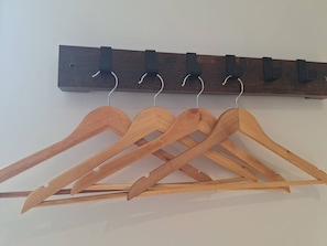 A wooden coat rack with multiple hangers.