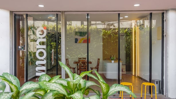 A modern interior with a reception desk, chairs, and potted plants. - Mono Coliving Kota Tua, Jakarta (Jakarta)