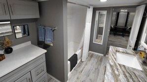 A modern bathroom with grey walls, a white countertop, and a shower area. - “Rancho” by the Lake 1 block from Lake Erie (Dunkirk)