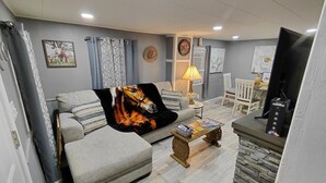 A living room with a sofa, a coffee table, a TV, and a lamp. - “Rancho” by the Lake 1 block from Lake Erie (Dunkirk)