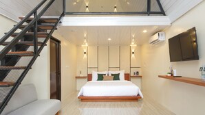 Un dormitorio moderno con cama, sofá, escalera, televisor montado y equipo de aire acondicionado.