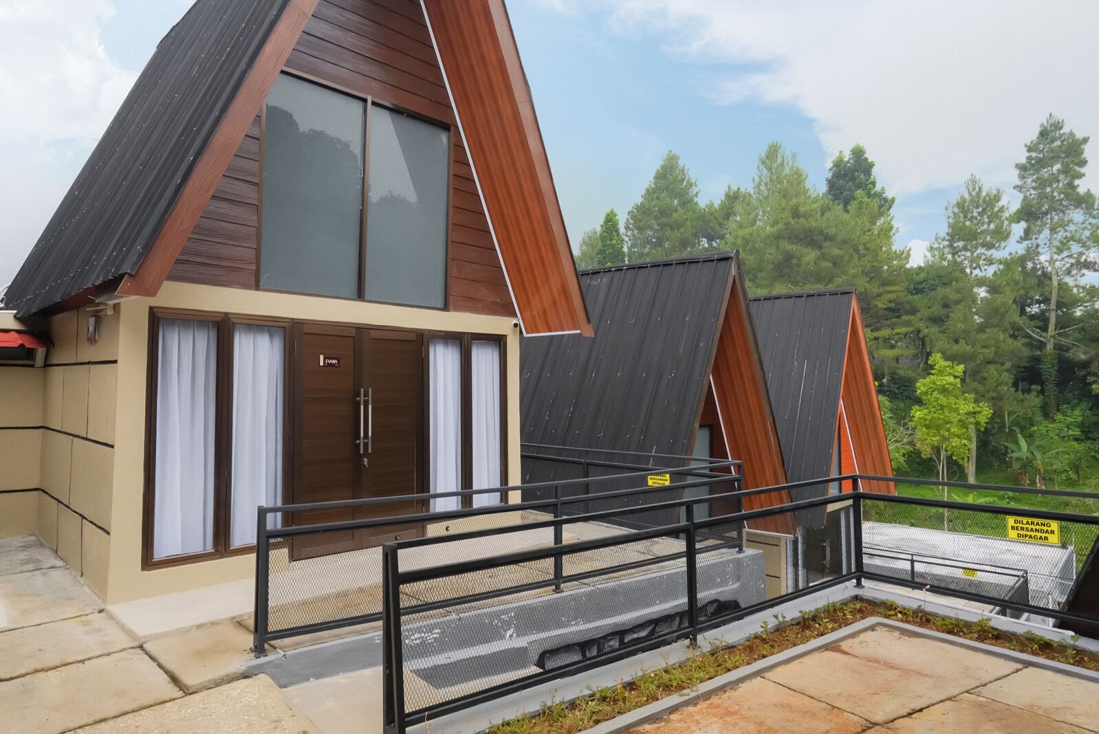 A modern house with a sloped roof, large windows, and a metal fence.