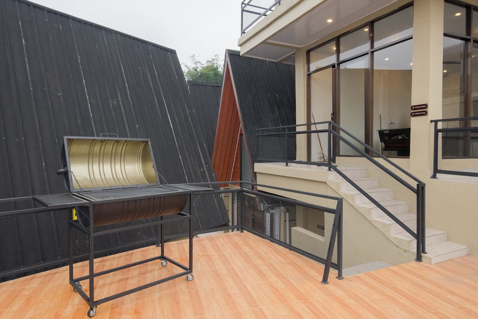 A modern outdoor area with a metal cart, a staircase, and a black wall.