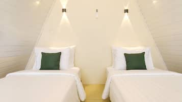Een kamer met twee bedden, elk voorzien van witte beddengoed en groene kussens, en een lichtgekleurde vloer.