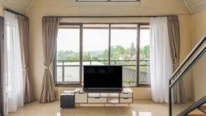 Un salón espacioso con un televisor grande, una mesita y una maleta.