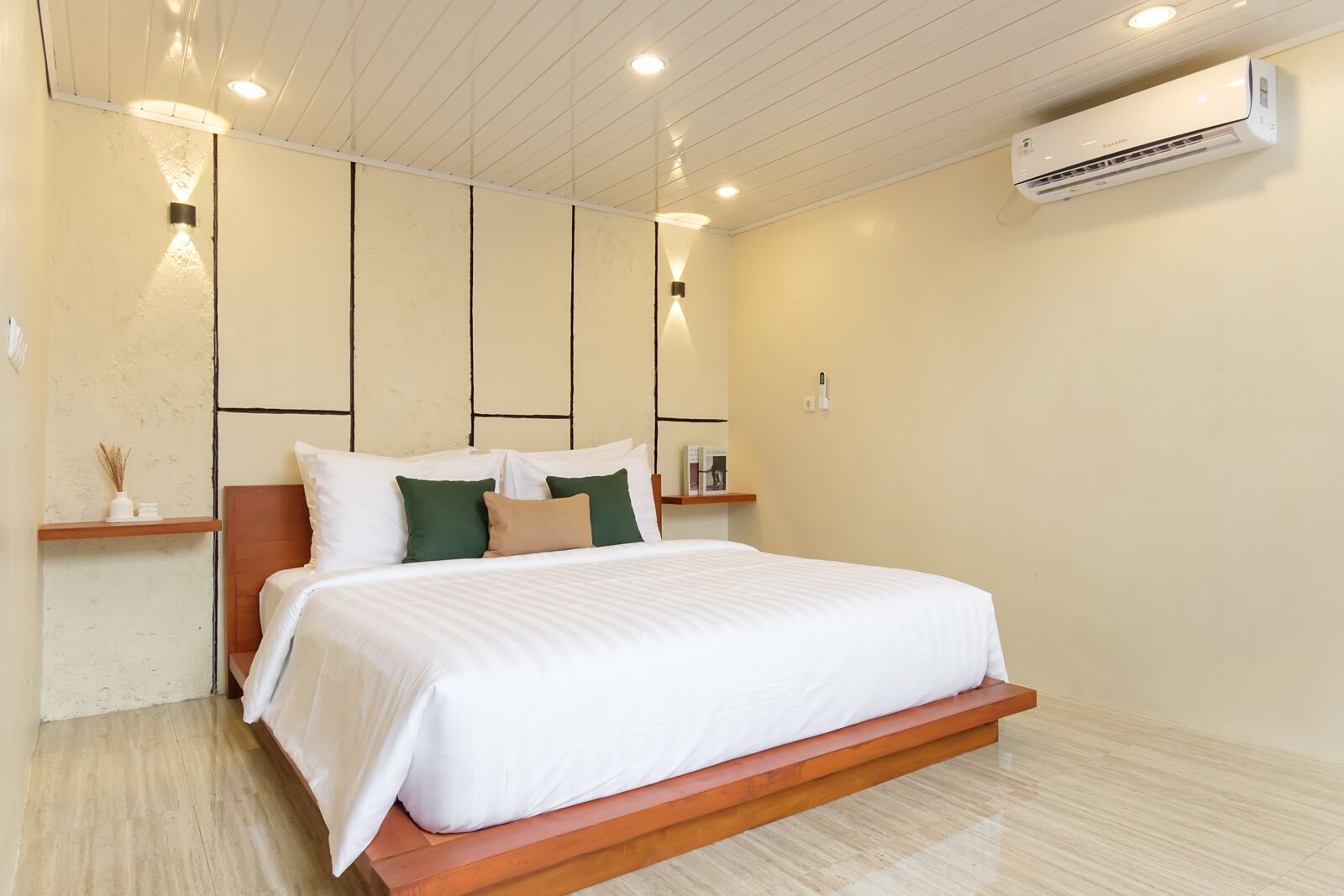 Un dormitorio moderno con cama, mesitas de noche, aire acondicionado de pared y luces empotradas en el techo.