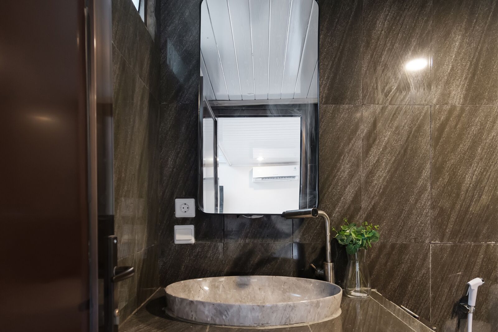 A modern bathroom with a round marble sink, a mirror, and a wall-mounted towel rack.