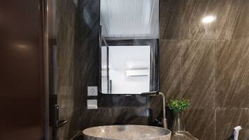 A modern bathroom with a round marble sink, a mirror, and a wall-mounted towel rack.