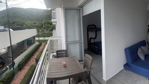 A balcony with a table and chairs, a blue sofa, and a view of a green landscape. - Rest apartment in Girardot. (Girardot)