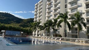 A hotel with a swimming pool, palm trees, and a mountainous backdrop. - Rest apartment in Girardot. (Girardot)