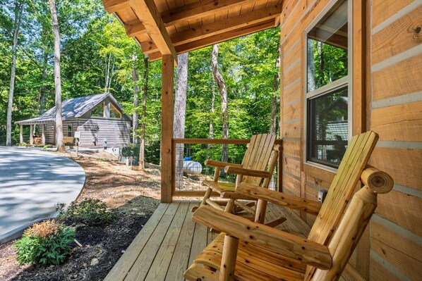 Una baita di legno con un portico e una zona salotto esterna coperta, con una finestra ben visibile.