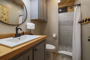 Bagno con lavandino, specchio, portasciuga, WC e doccia.