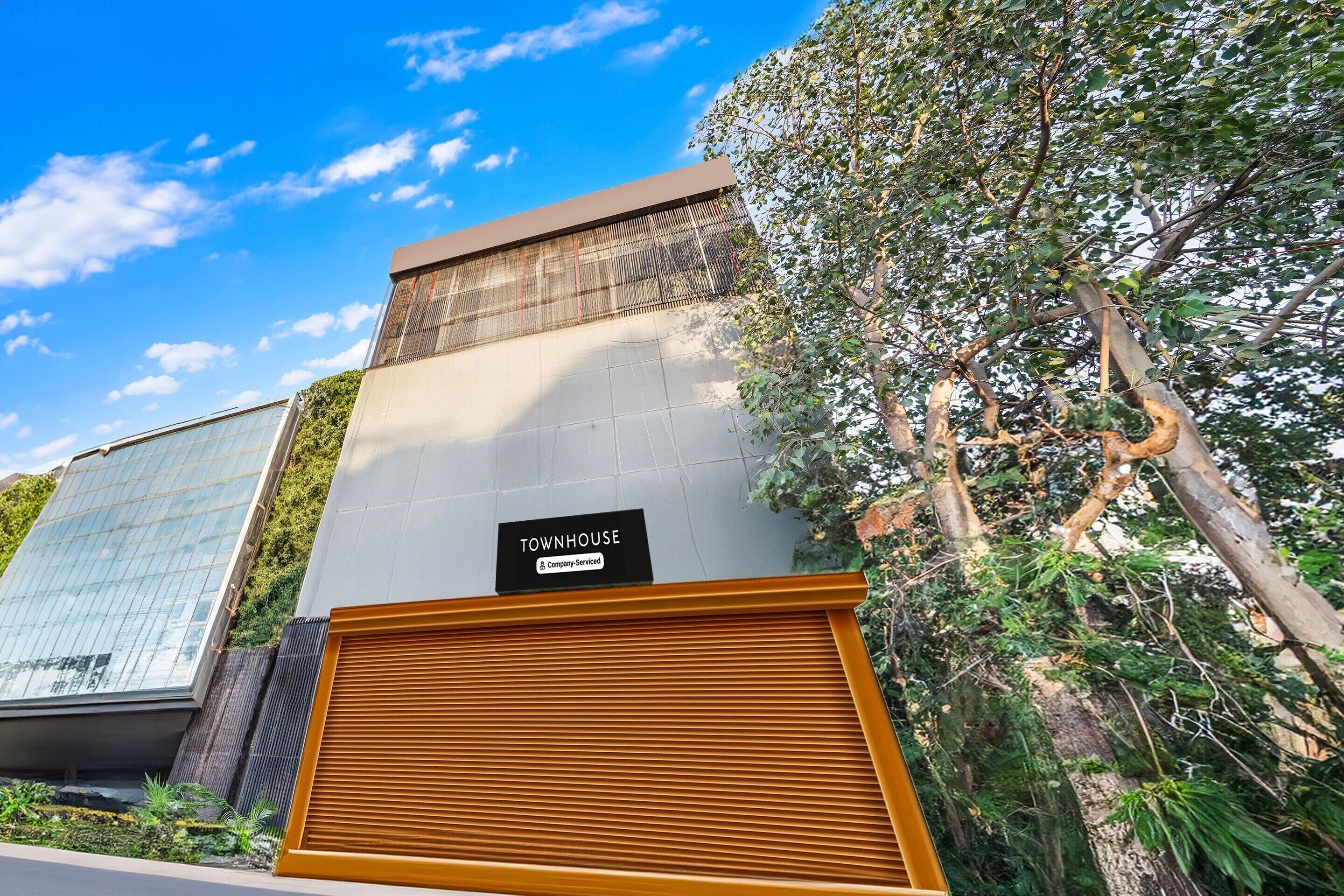 A modern building with a sign indicating it is a company-serviced townhouse.